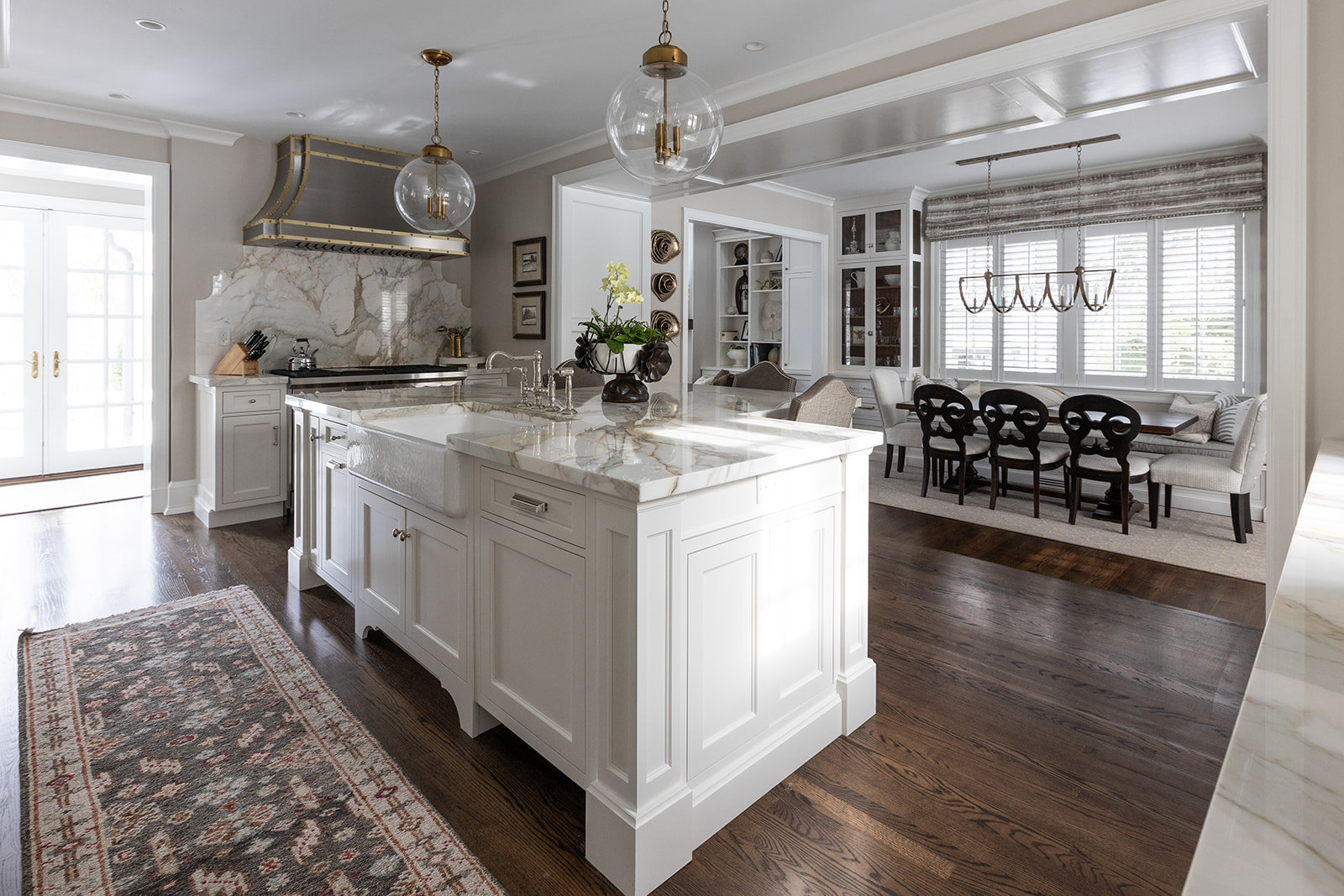 Scherr kitchen with a marble island, apron-front sink, and brass pendants